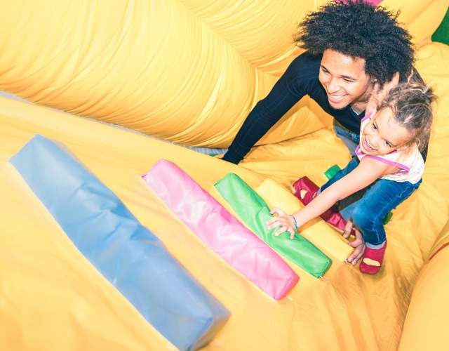 Father and daughter climbing bouncy castle