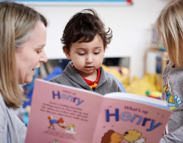 Woman reading a HENRY story book to two young children