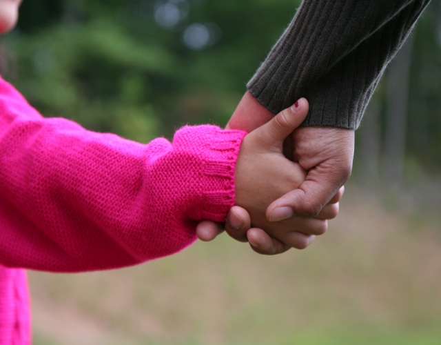 Child in pink holding adult's hand