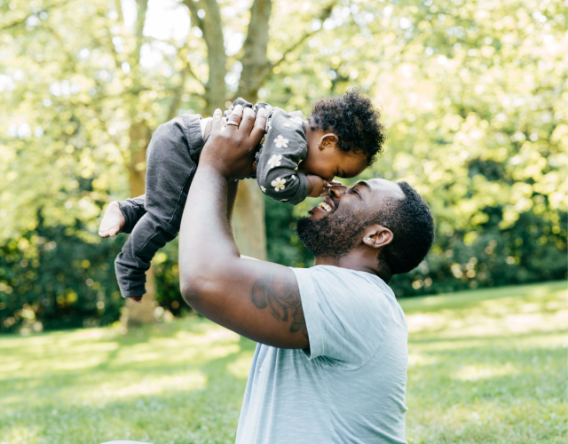 African dad playing with his daughter outside