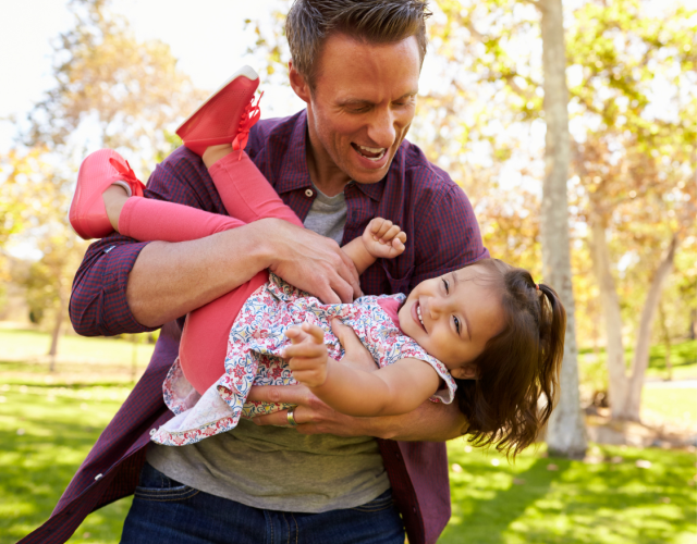 Dad playing with his daughter in a park