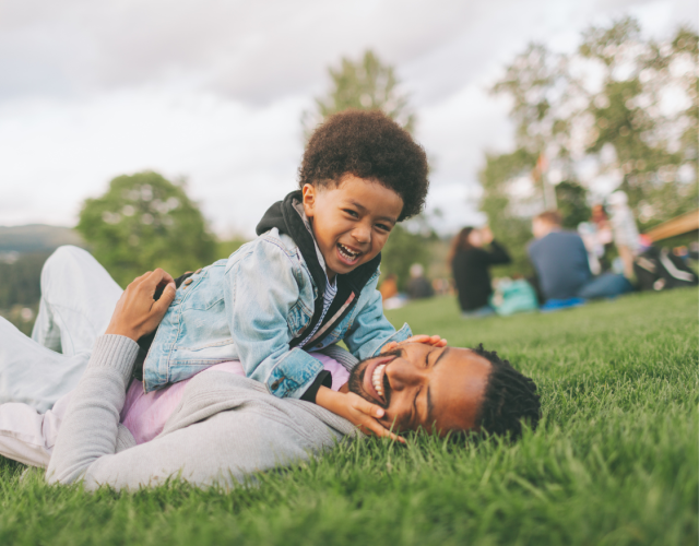 Little African boy playing with his dad in the park