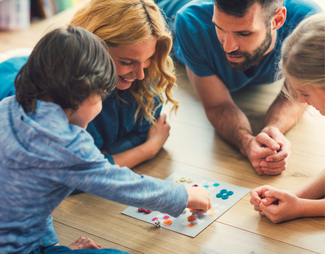 family playing a board game together laying on the floor