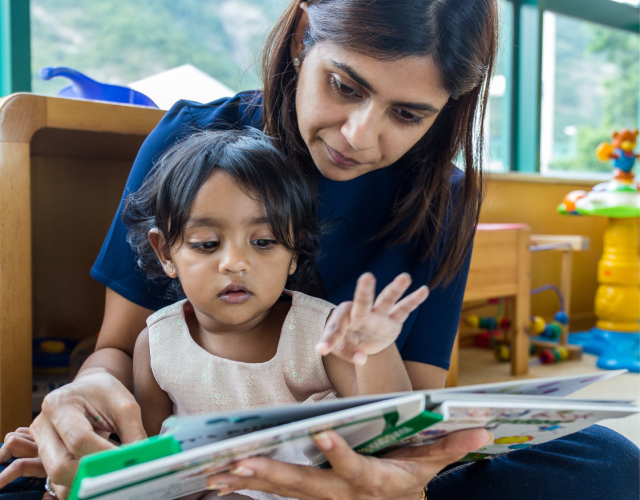Asian woman reading a book to her child