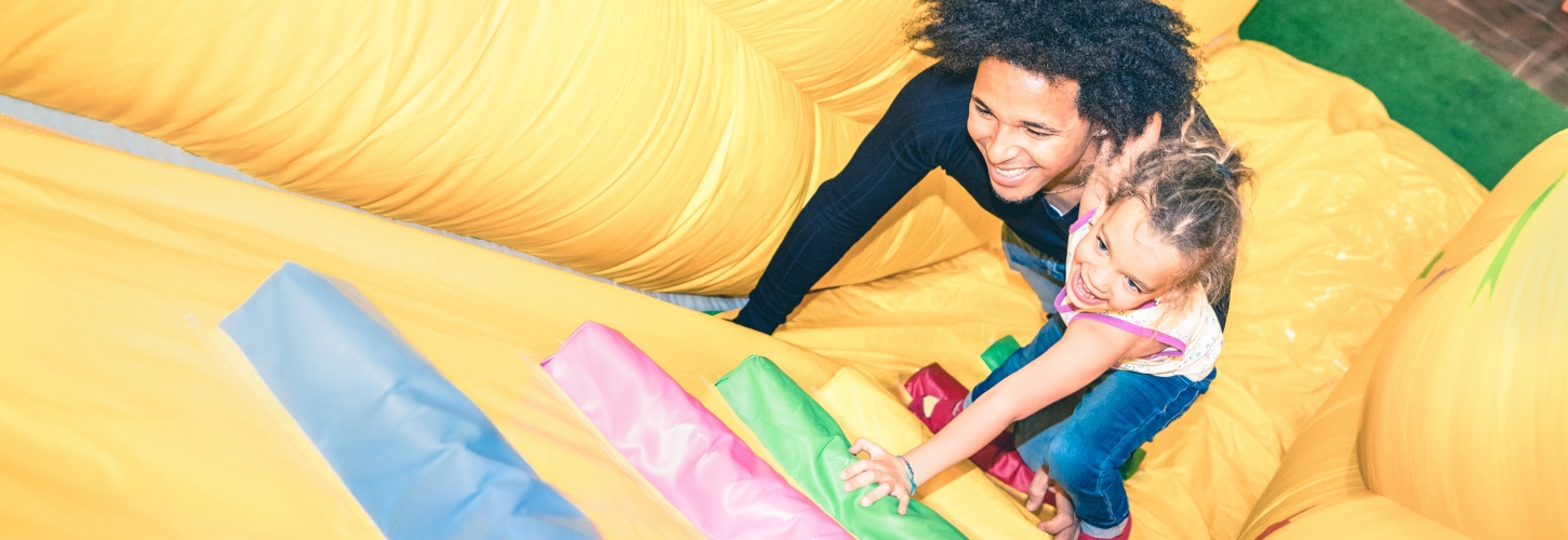 Father and daughter climbing bouncy castle together