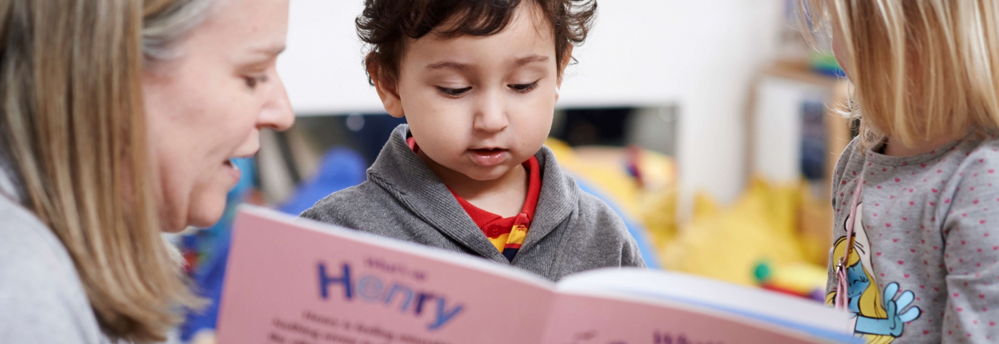 Woman reading a HENRY story book to two young children