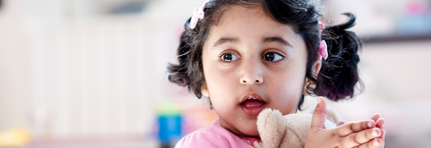 asian toddler girl in pink shirt clapping hand and holding a teddy bear