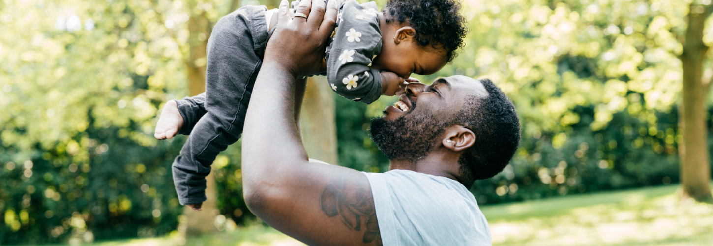 African dad playing with his daughter outside