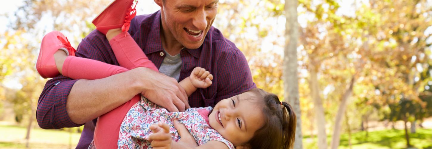 Dad playing with his daughter in a park