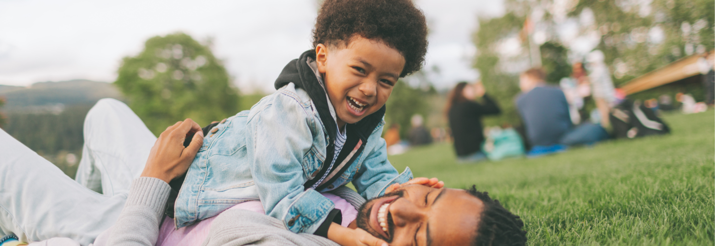 Little African boy playing with his dad in the park