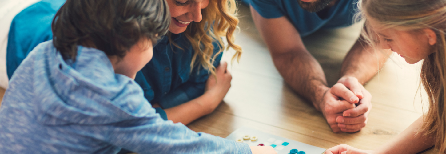 family playing a board game together laying on the floor